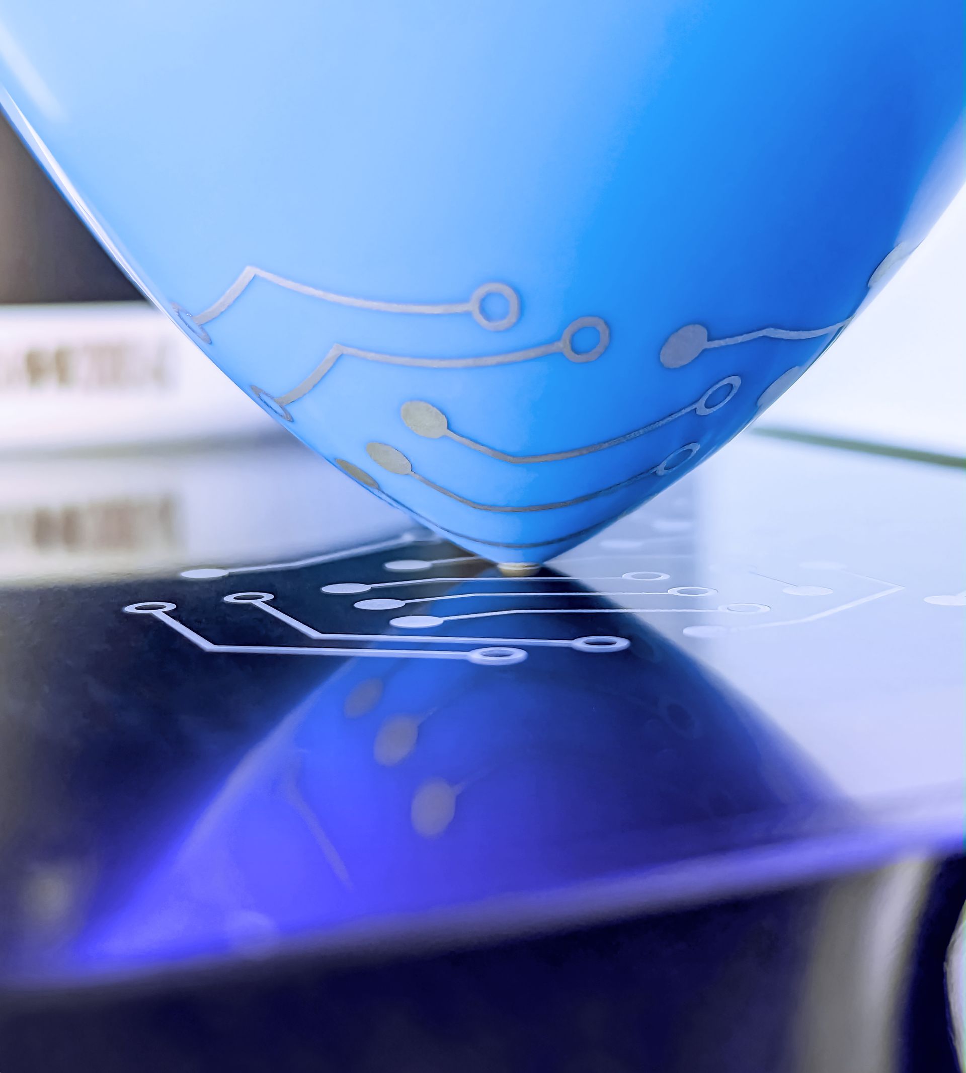 Eine blaue Tampondruckmaschine liegt auf einer schwarzen Oberfläche.