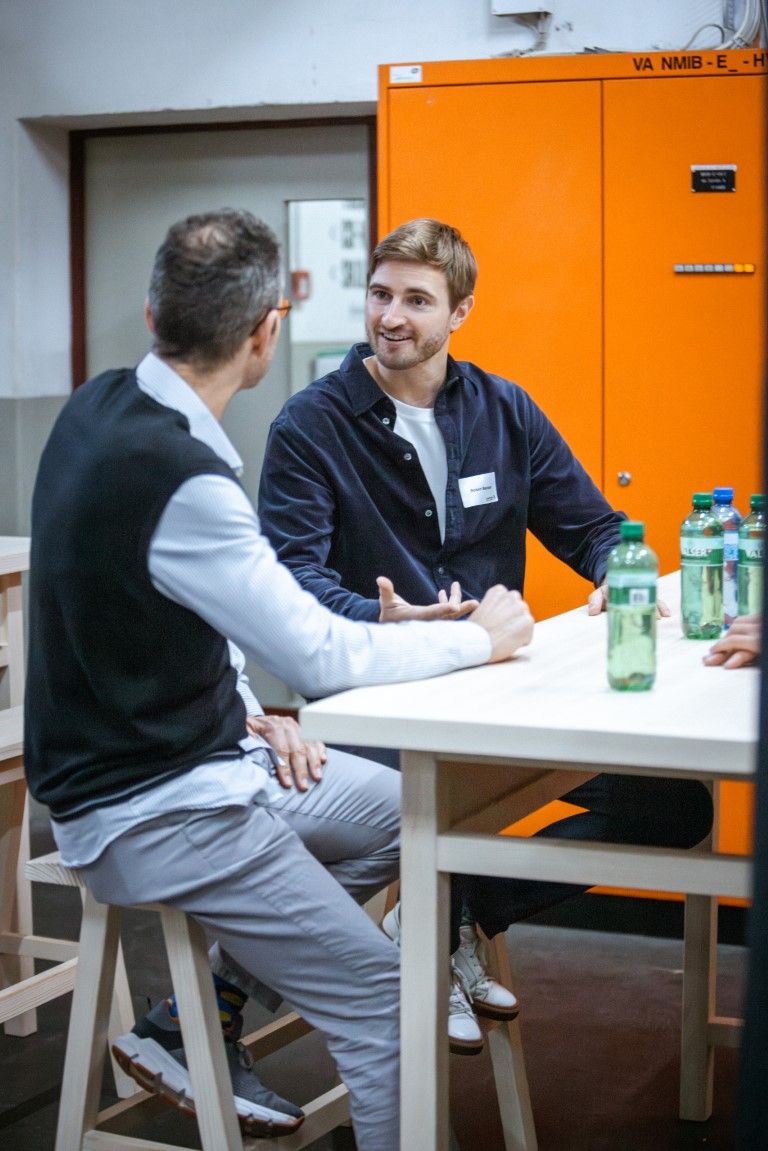 Zwei Männer sitzen an einem Tisch und unterhalten sich.