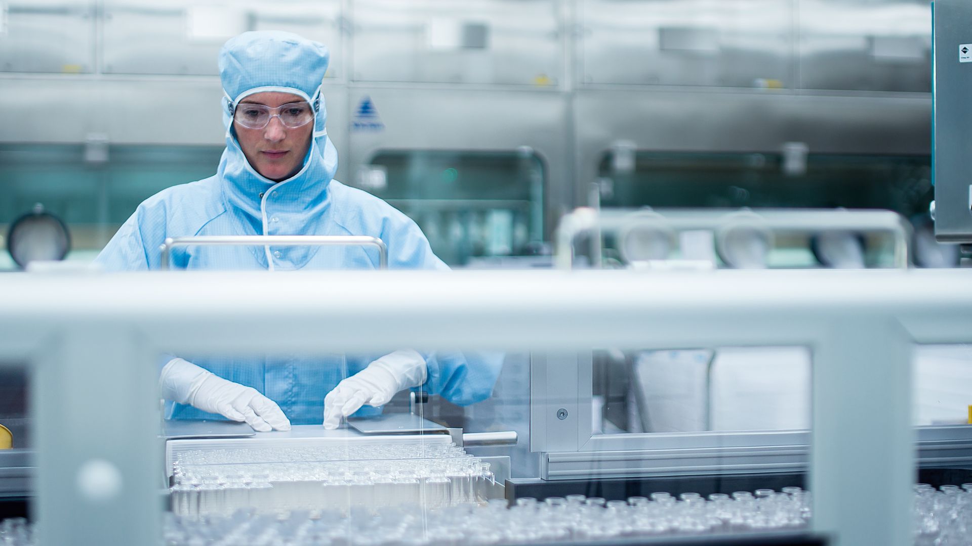 Eine Frau arbeitet in einem Reinraum an einer Maschine in einer Fabrik.