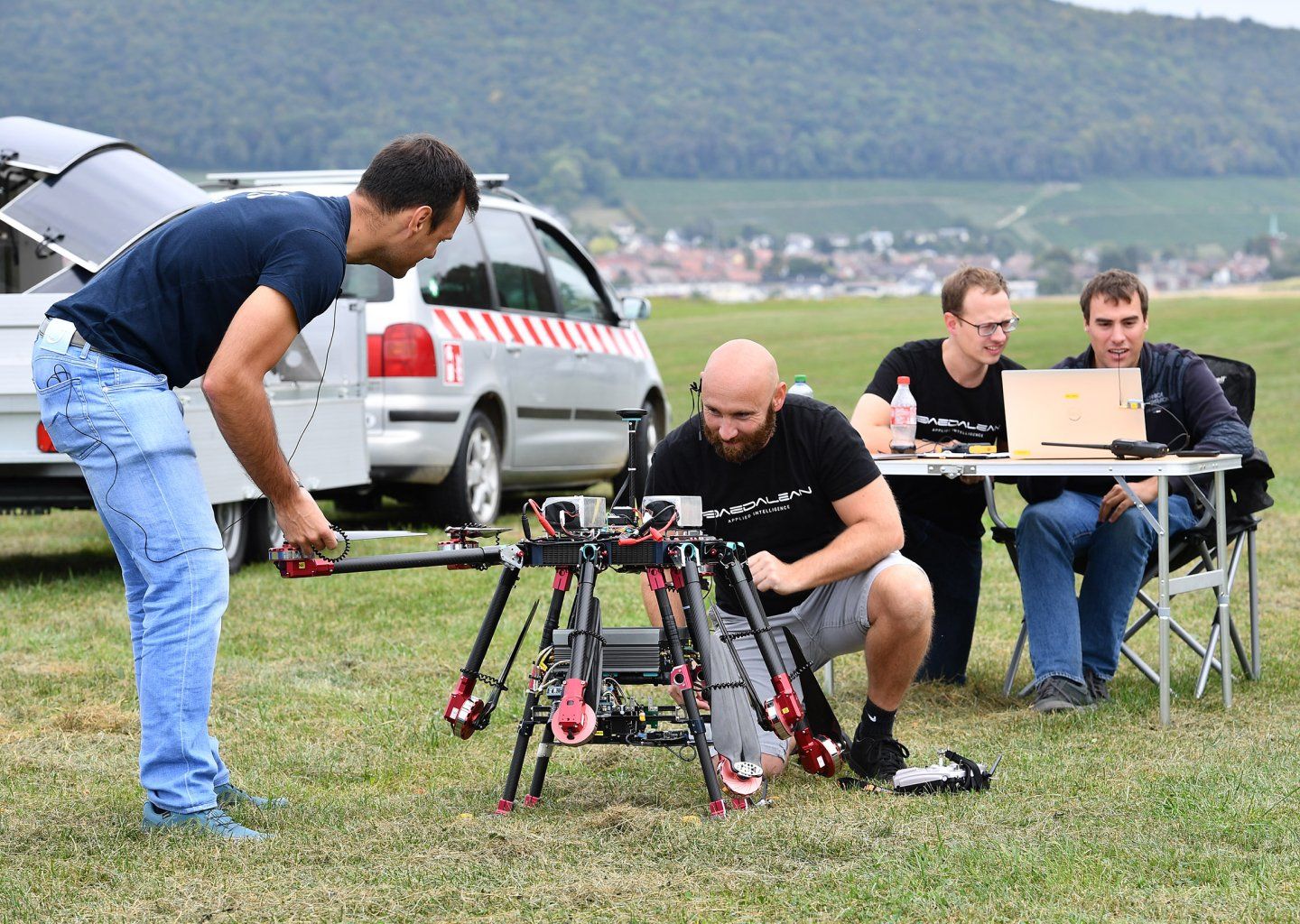 Eine Gruppe Männer arbeitet auf einem Feld an einer Drohne.