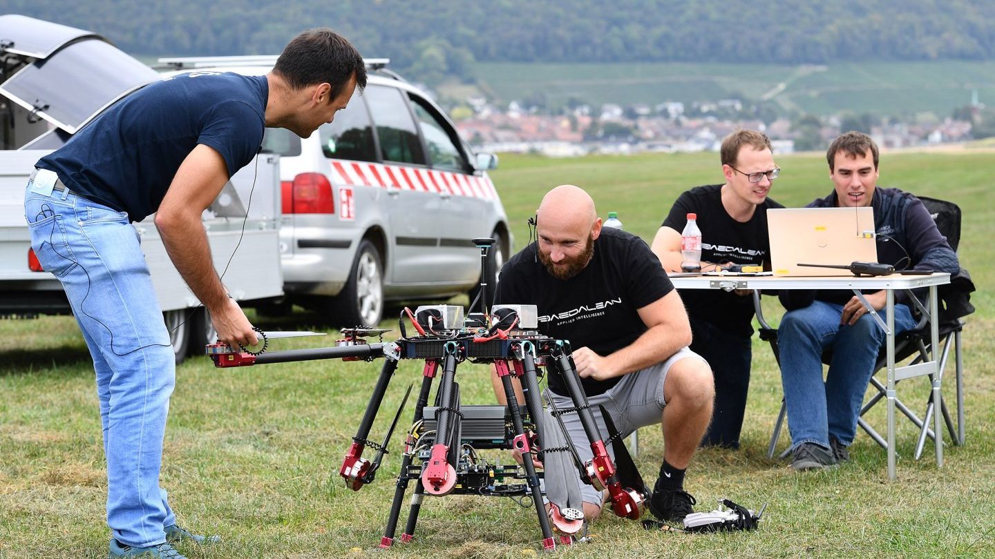 Eine Gruppe Männer arbeitet auf einem Feld an einer Drohne.