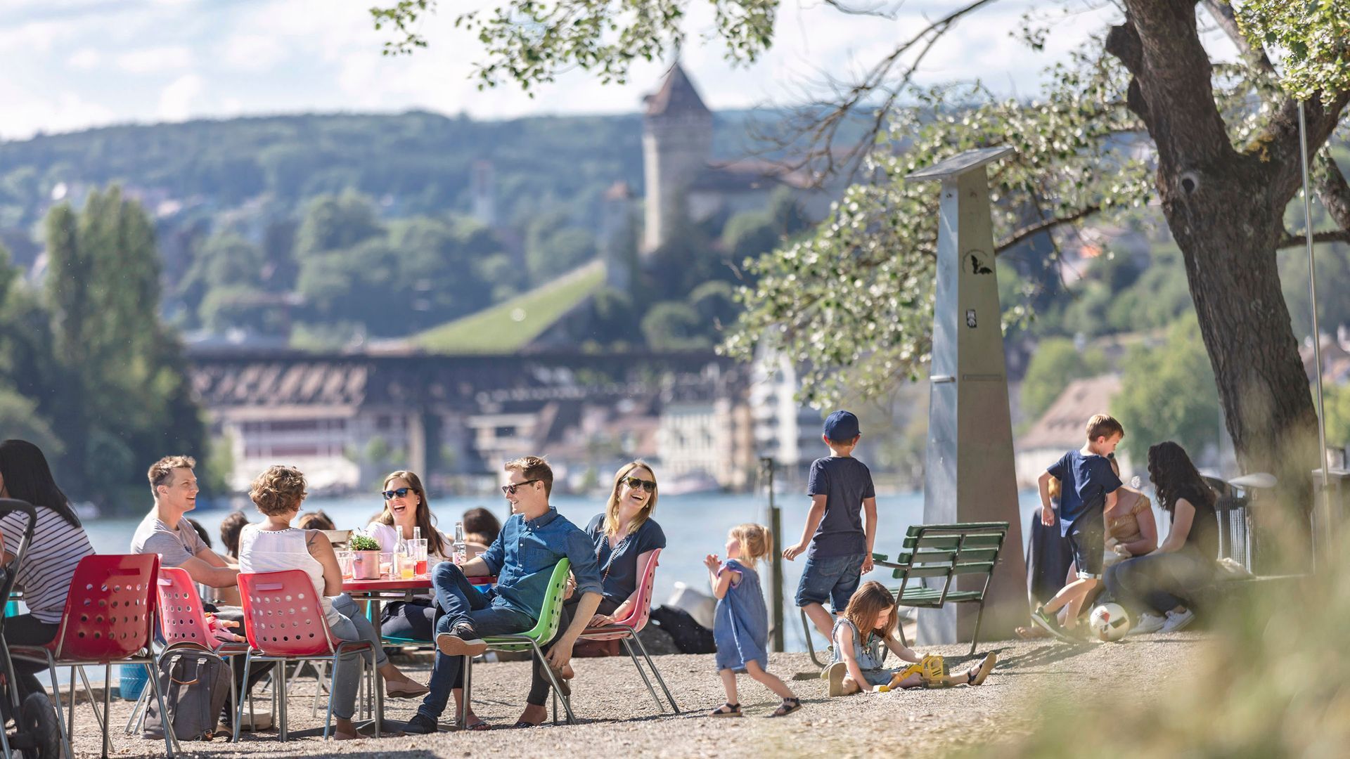A group of people are sitting at tables near the rhine in Schaffhausen, Switzerland.